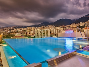 A swimming pool with a view of a cityscape and mountains in the background.
