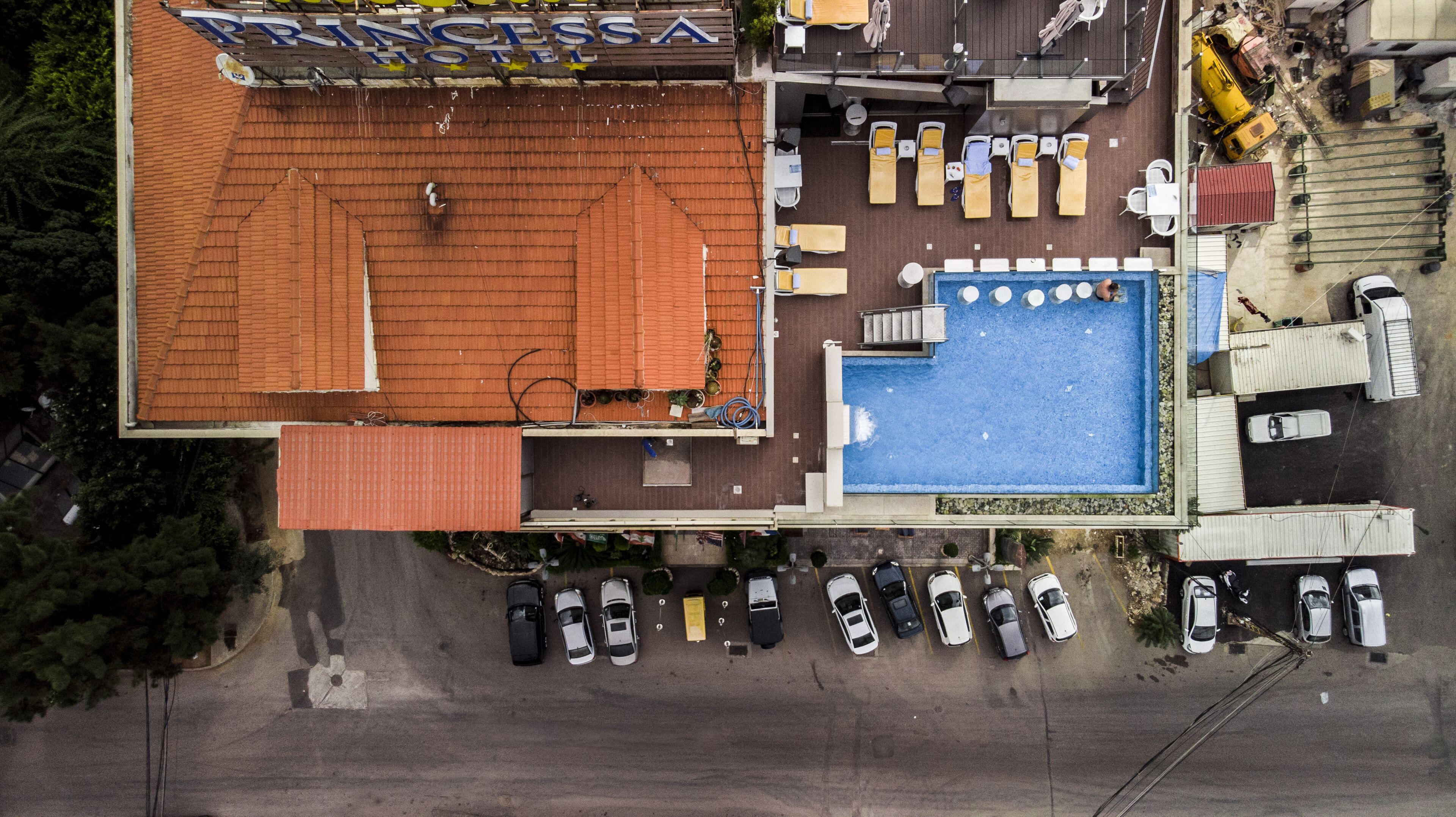 Vista aérea de un hotel con piscina, sillas de descanso y un área de estar al aire libre cubierta.