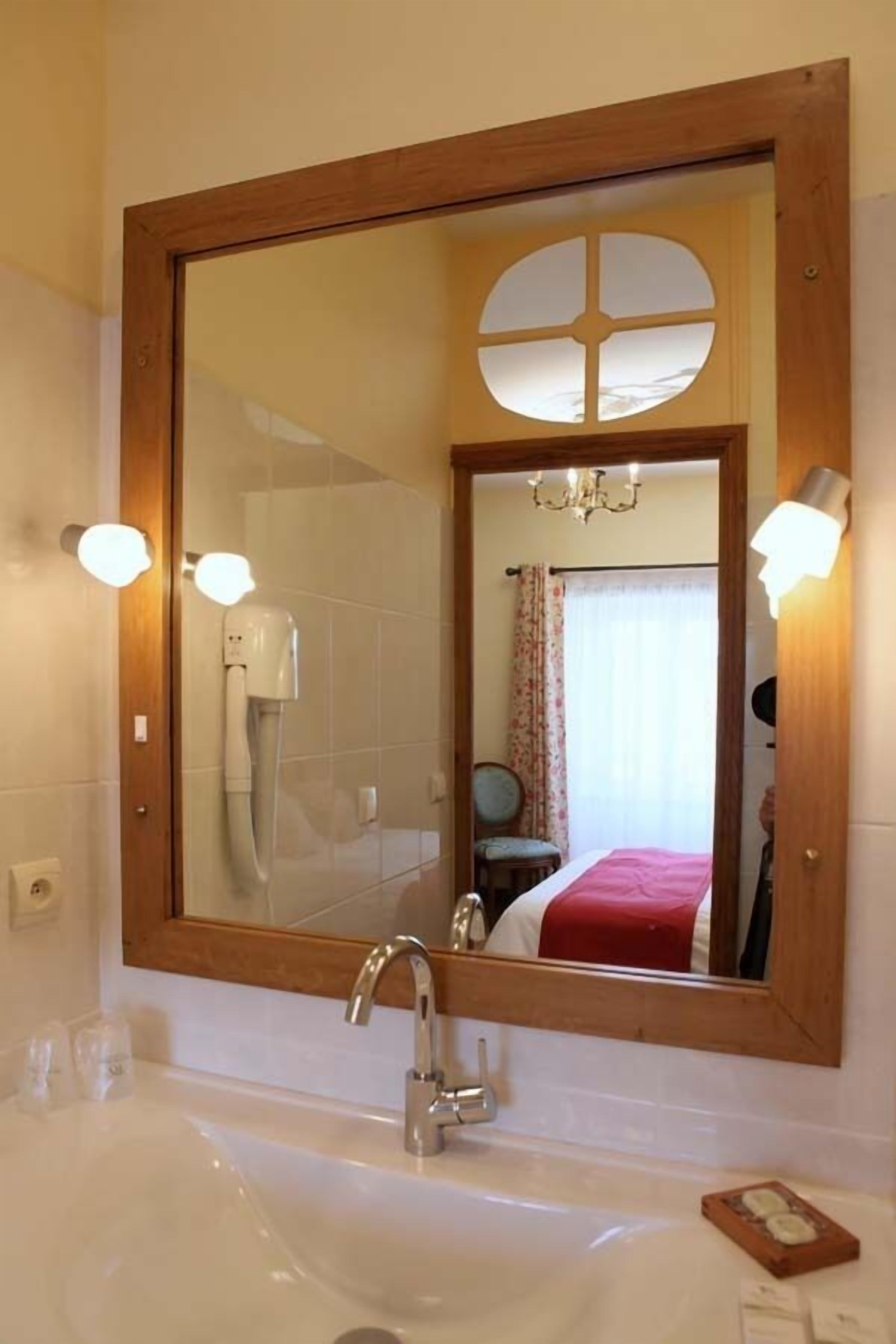 Un bagno con uno specchio grande, un lavandino, un asciugacapelli e un lampadario.