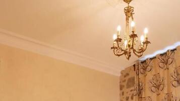 A bedroom with a large bed, two bedside tables, a chandelier, and patterned curtains.