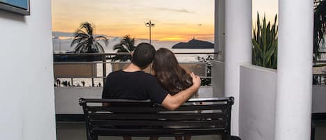 Una coppia seduta su una panchina di fronte a un panorama al tramonto.