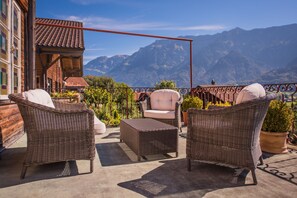 Una terraza con mobiliario de mimbre y vistas a montañas.