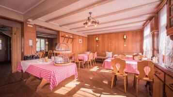 Un comedor con paredes de madera, manteles a cuadros y una araña.