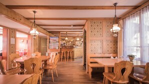 A restaurant with wooden furniture, hanging lights, and patterned wallpaper. - Gasthof Schoenegg (Ringgenberg)