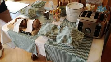Ein Tisch, gedeckt mit einer karierten Tischdecke, einem Brotlaib, einem Toaster und verschiedenen Küchenutensilien.
