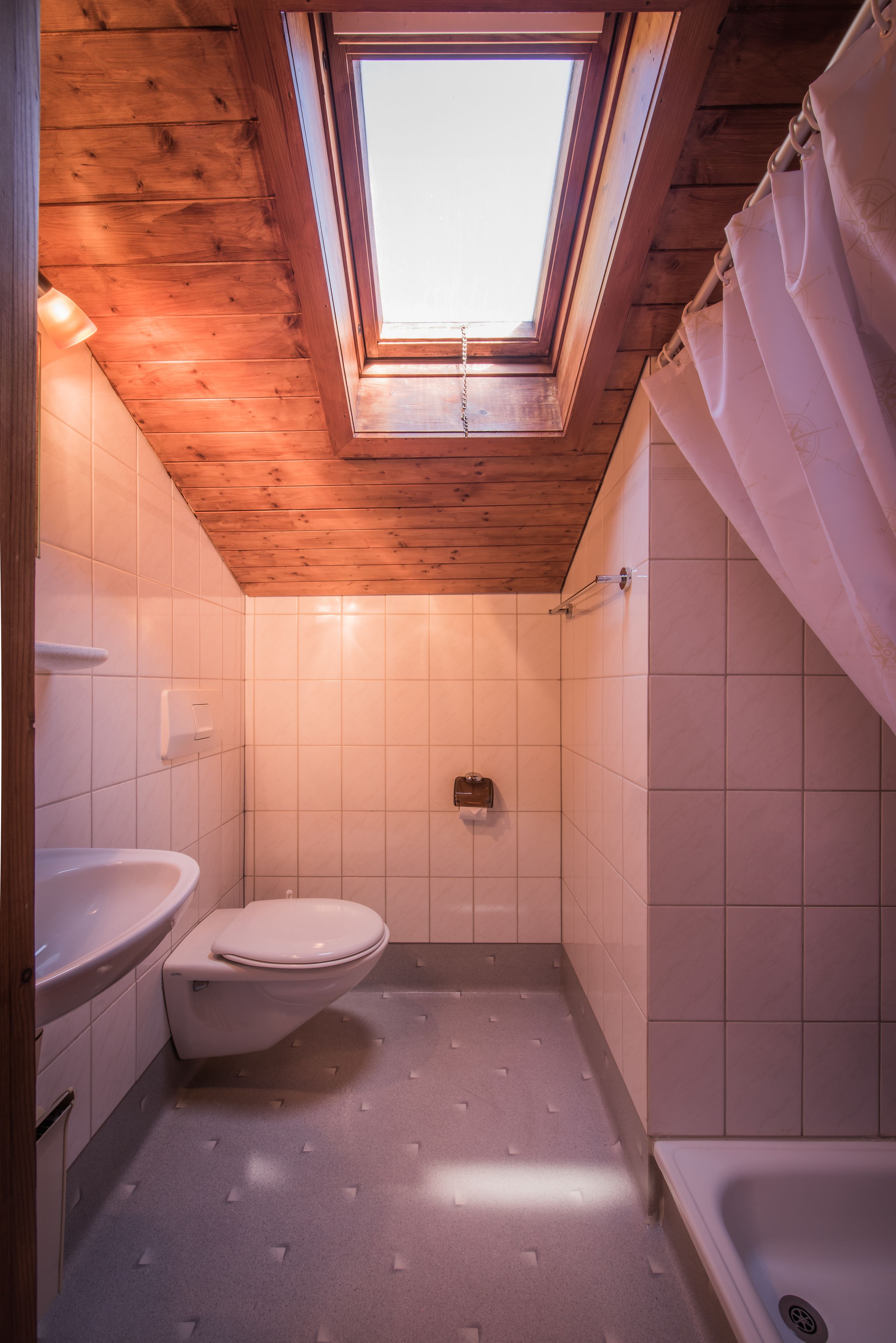A small bathroom with a skylight, a toilet, a sink, and a bathtub.