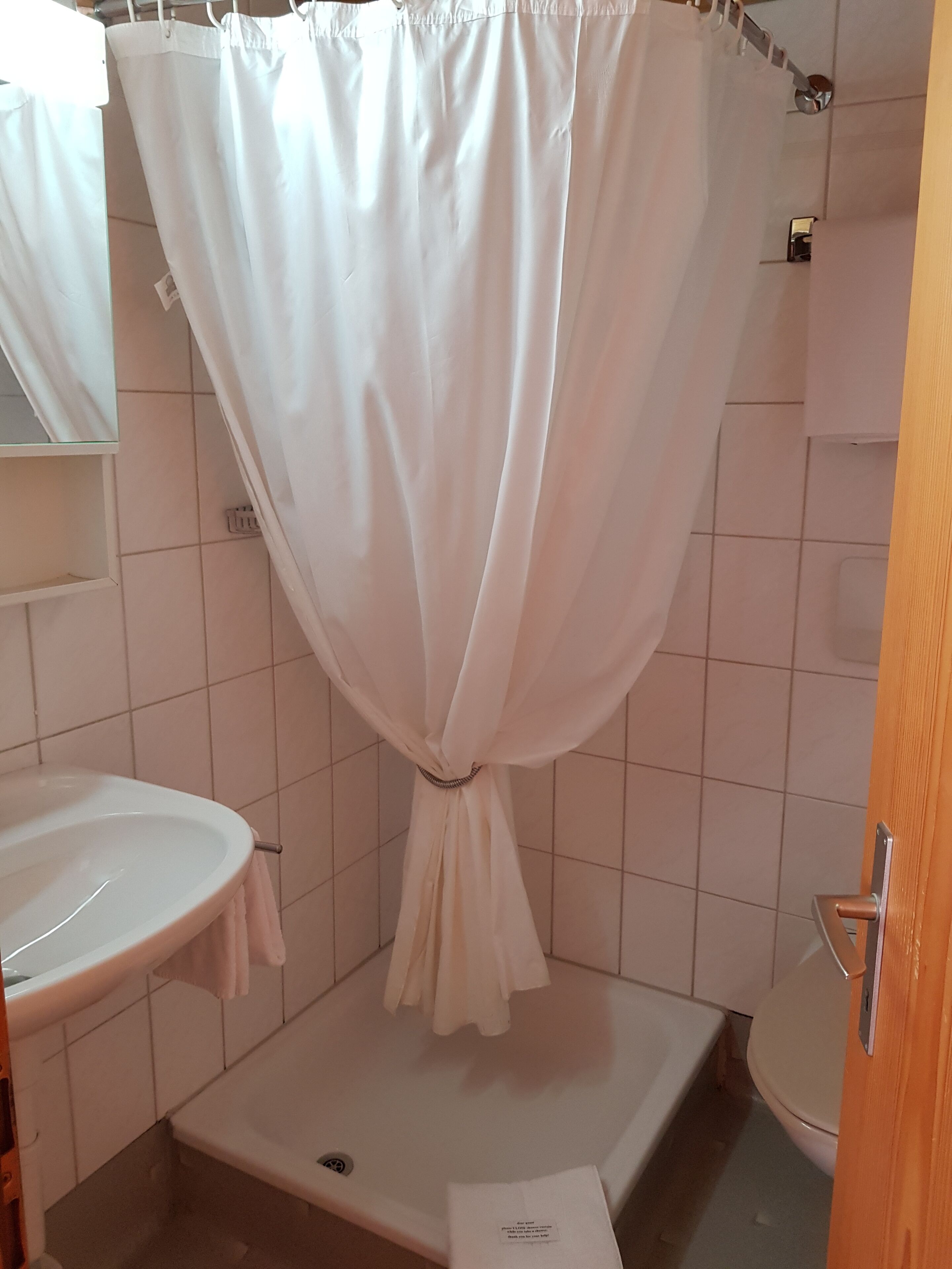 A bathroom with a shower curtain tied at the bottom, a sink, and a toilet.