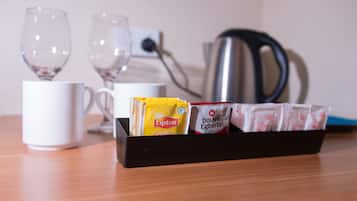Een dienblad met Lipton en Douwe Egberts theezakjes, een witte mok en twee glazen op een houten tafel.
