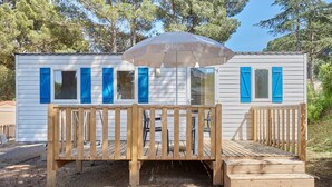 A small, single-story wooden structure with a deck and an umbrella. - Domaine de Plein Air Odalys La Pinède (Agde)