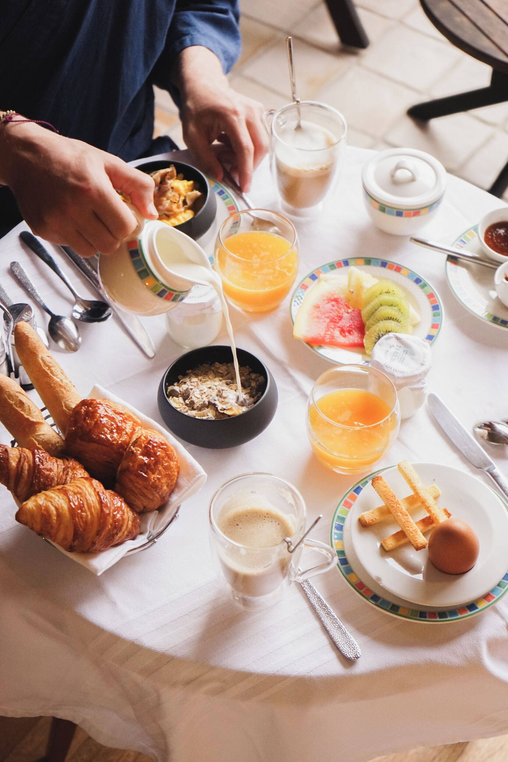 A breakfast table with croissants, fruit, and beverages.