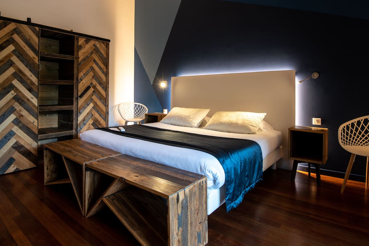 A bedroom with a bed, wooden bench, and a herringbone-patterned wardrobe.