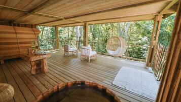 Relax on the deck with a hot tub, seating, and a small table.