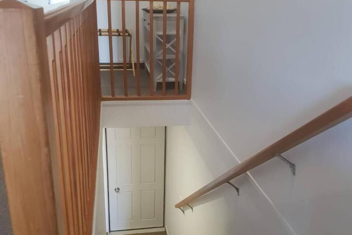A staircase with wooden railings and a white door at the bottom.