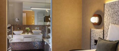 Habitación de hotel con cama, baño con espejo, lavabo y pared con diseño.