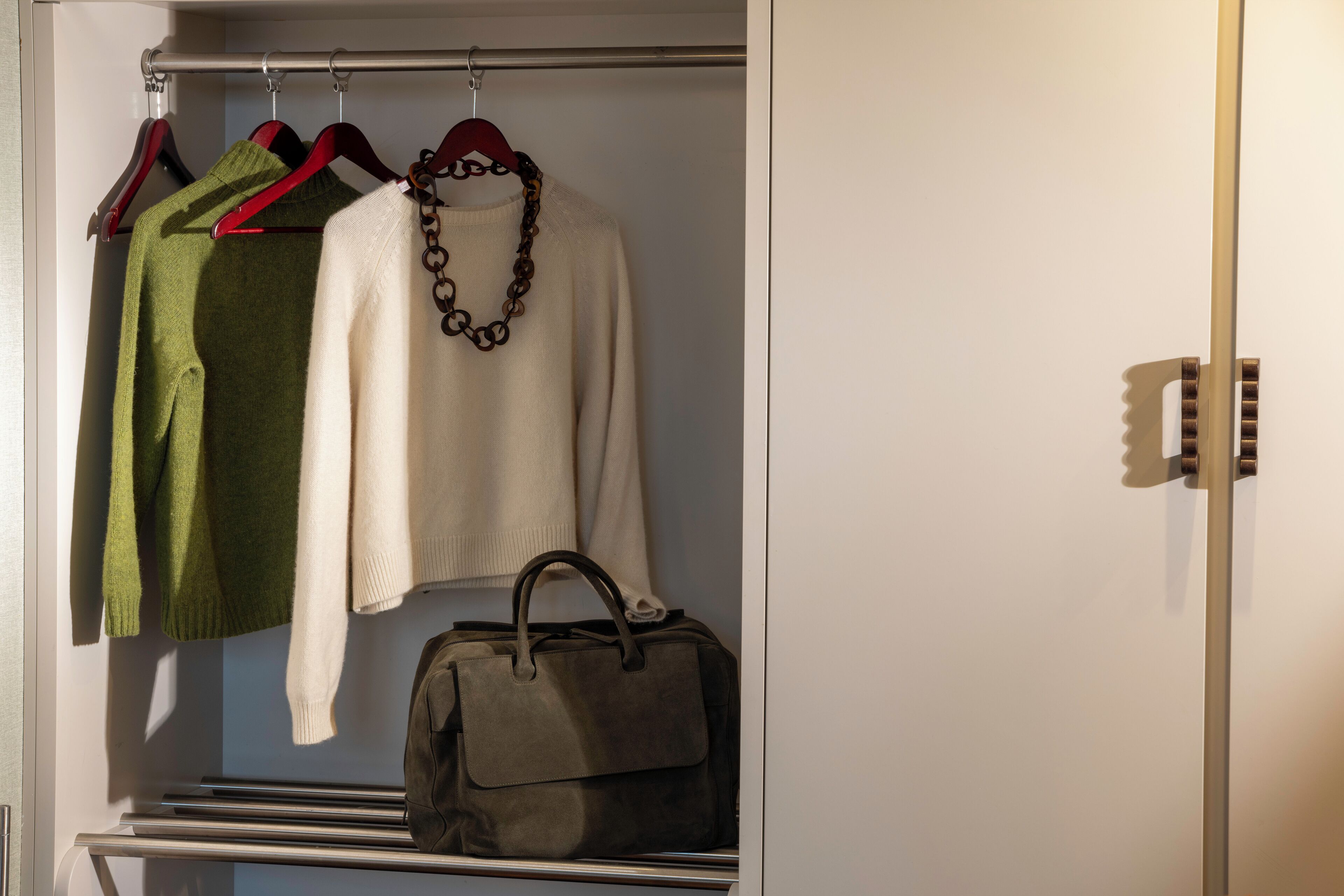 A closet with hanging clothes and a handbag.