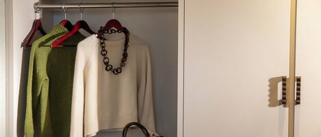 A closet with hanging clothes and a handbag.
