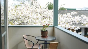 Een balkon met twee rieten stoelen en een kleine tafel met een bloempot.