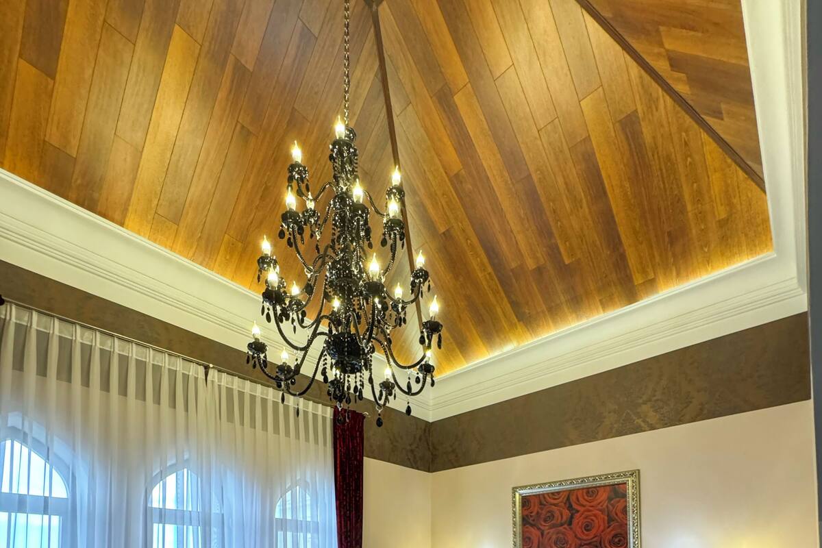 A bedroom with a large bed, a chandelier, and a painting on the wall.