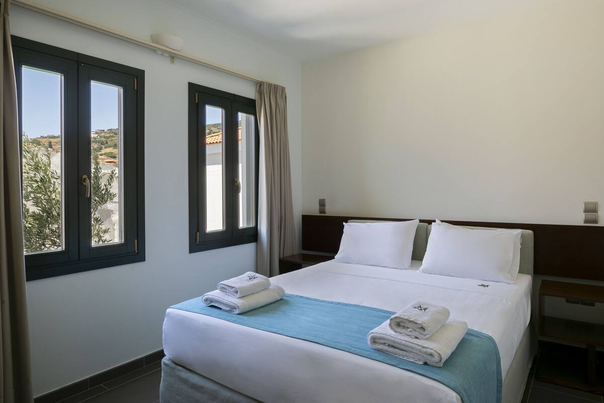 Une chambre d’hôtel avec un lit, deux fenêtres et une vue sur le paysage.