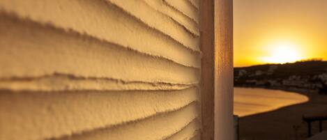 A close-up of a textured wall with a view of a sunset over a landscape.