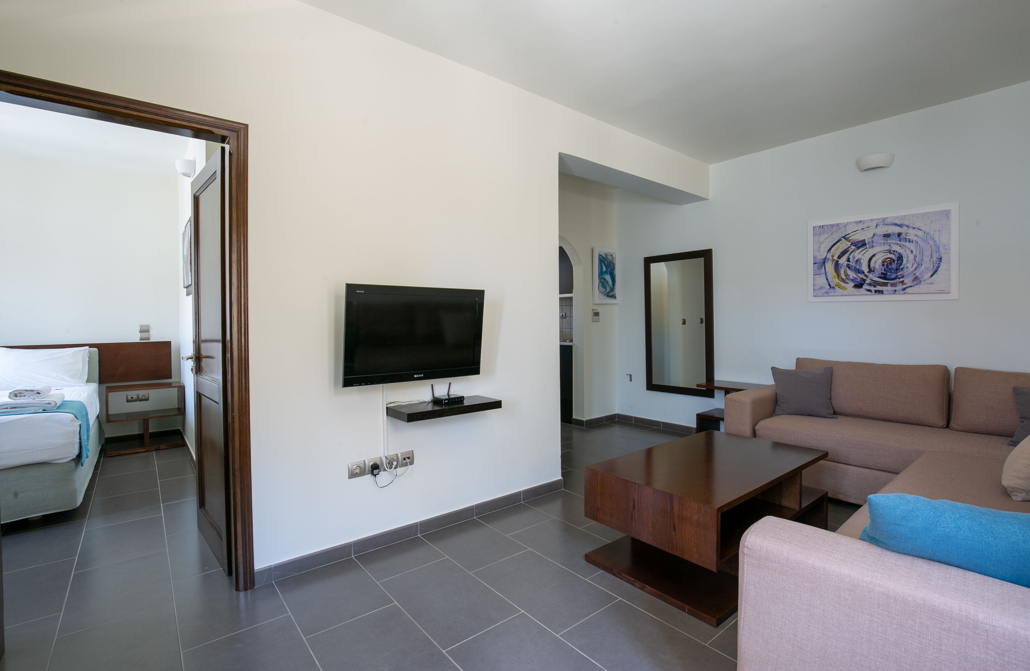 Una habitación de hotel moderna con televisión de pantalla plana, un sofá, una mesa de centro y una cama.