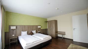 Una habitación de hotel con una cama grande, cabecero de madera, un escritorio y un armario.
