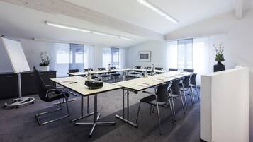 Ett konferensrum med ett långt bord, stolar, en whiteboard och en projektor.