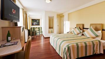 A hotel room with a bed, a TV, a desk with a chair, and a dining area.