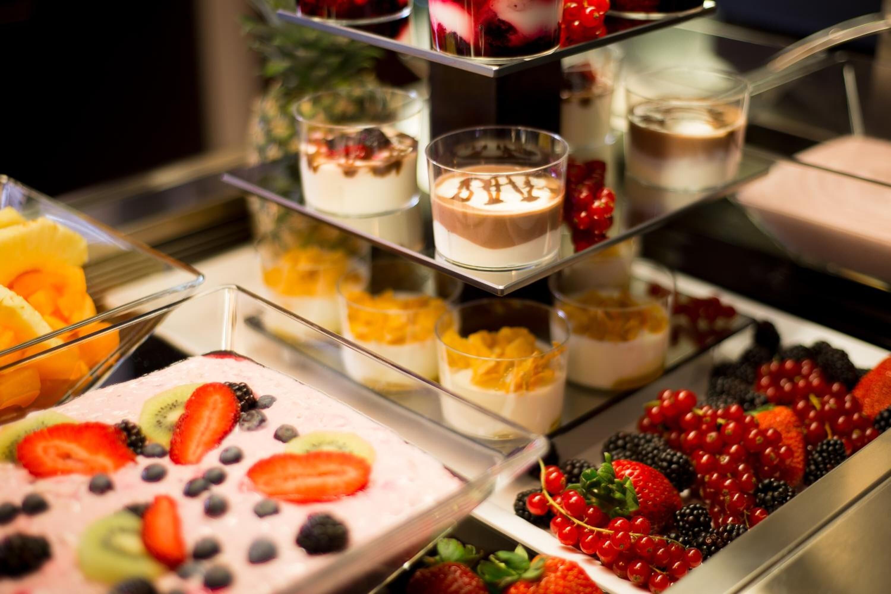 A dessert display with various fruit-topped desserts and beverages.