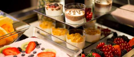 Una mesa de postres con diferentes opciones de dulces y bebidas cubiertas de fruta.