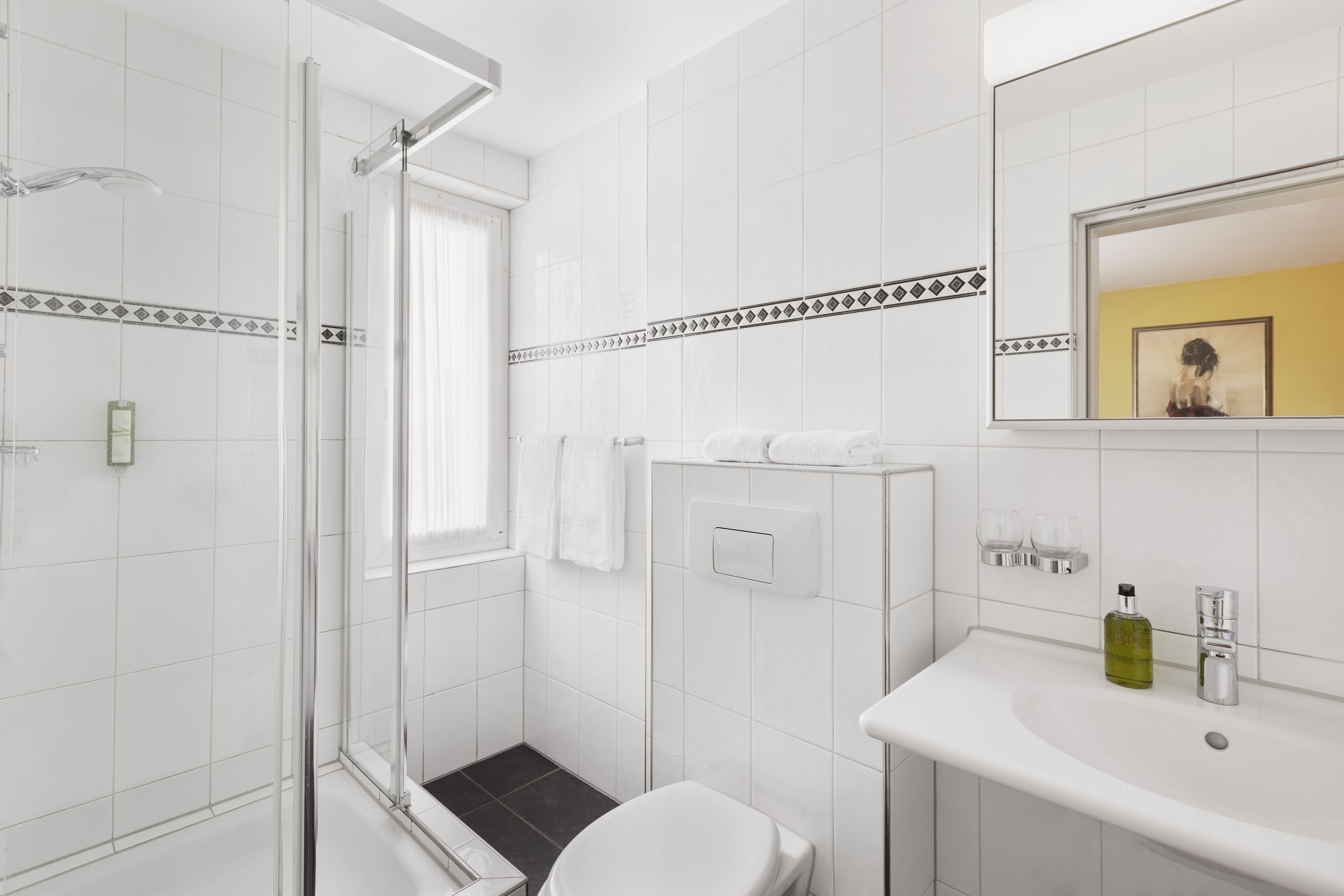 A modern bathroom with a glass shower enclosure, a white sink with a mirror, and a toilet.
