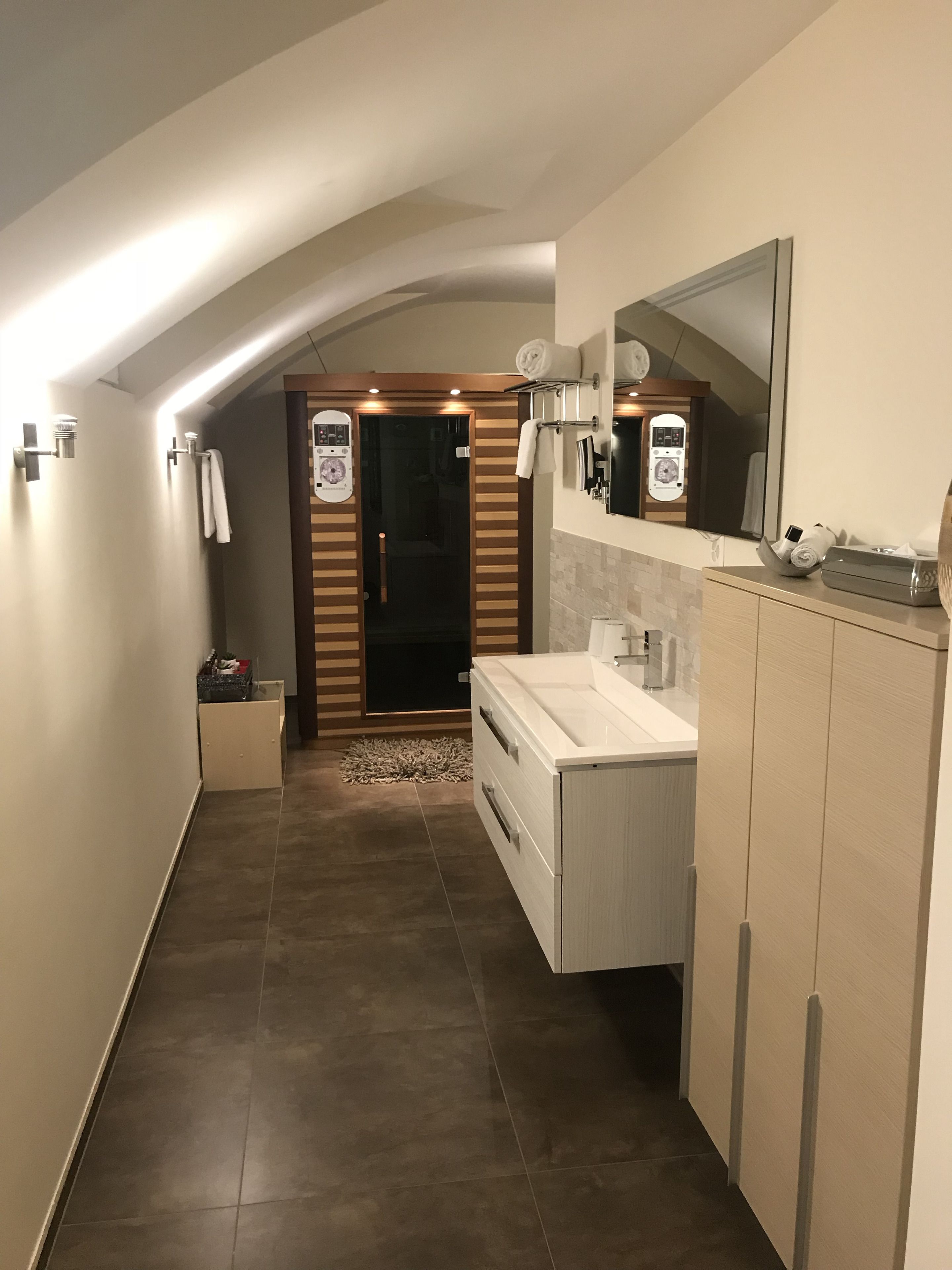 A modern bathroom with a vanity, a large mirror, and a shower area.