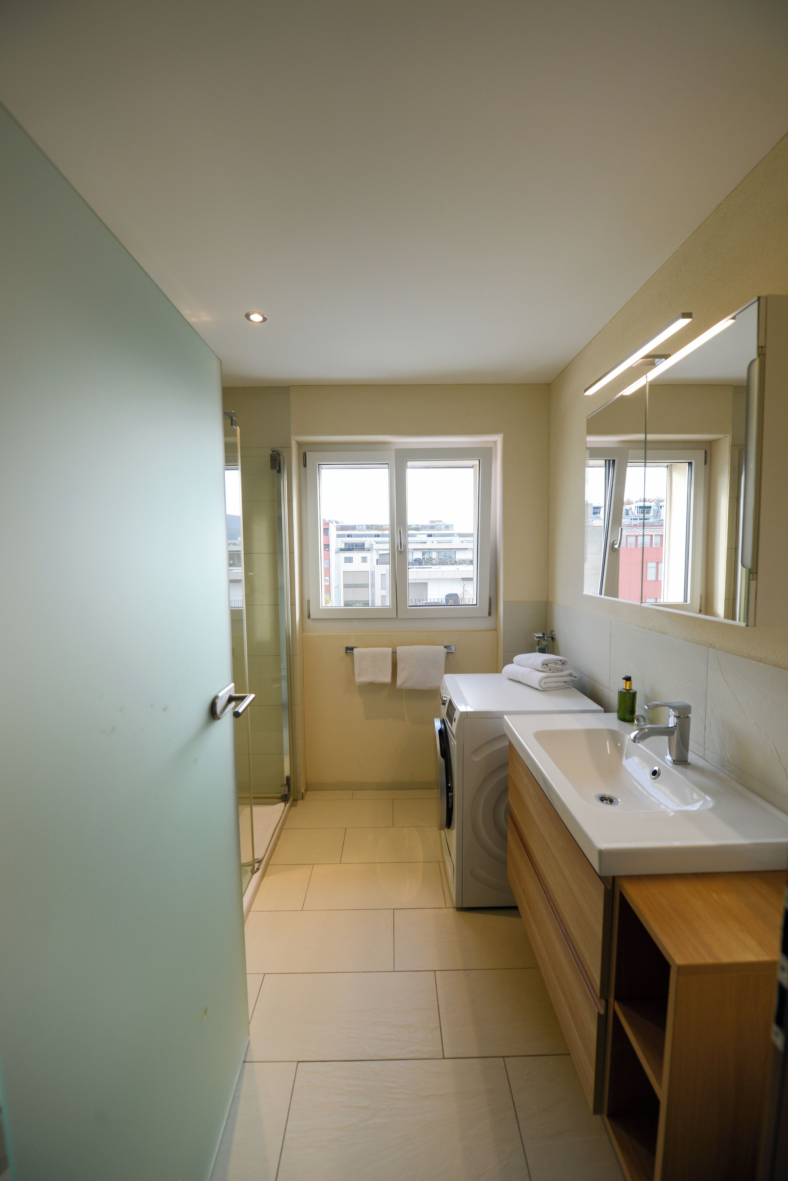 Une salle de bain moderne avec une grande fenêtre, un lavabo et un miroir.