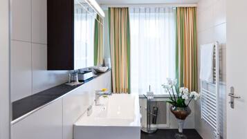 Un baño moderno con un espejo grande, un lavabo blanco y una zona de ducha.