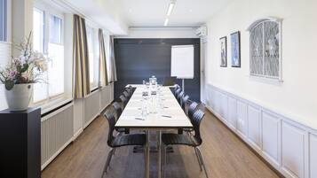 A conference room with a long table, chairs, a projector screen, and artwork on the walls.