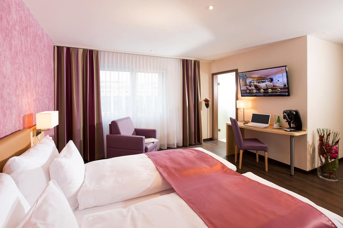 A hotel room with a bed, desk, and TV.