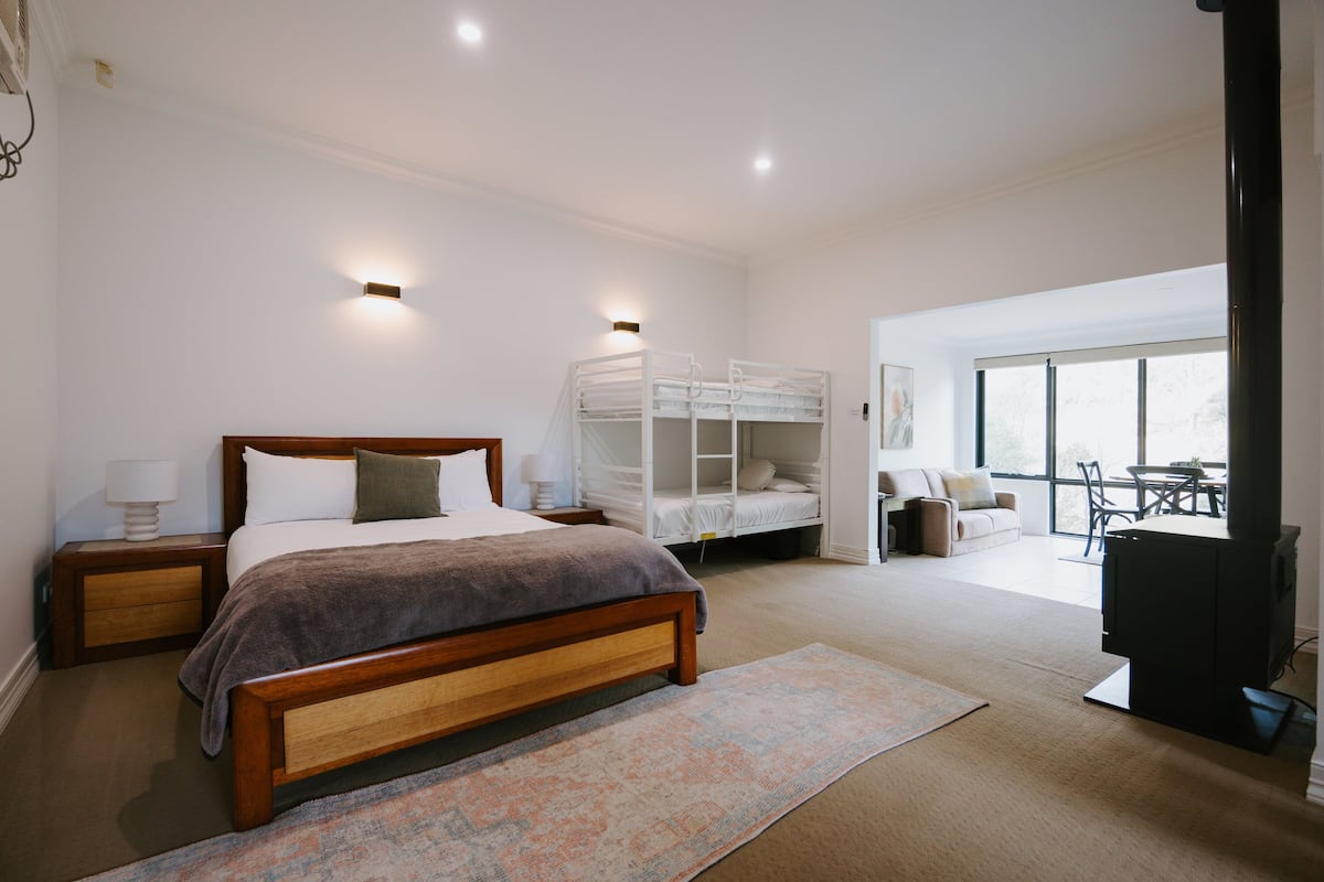 A bedroom with a wooden bed, a white canopy bed, a television, and a large window.