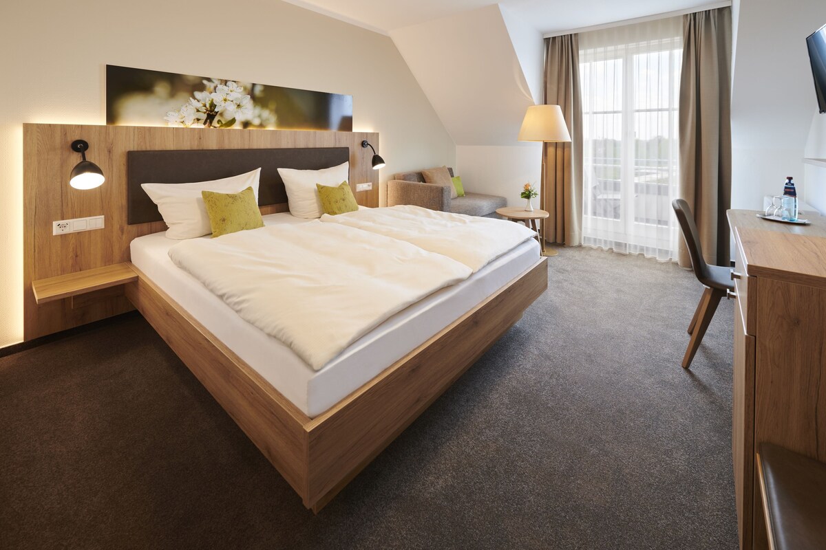 Una habitación de hotel con una cama grande, un escritorio, una silla, una lámpara y un televisor.