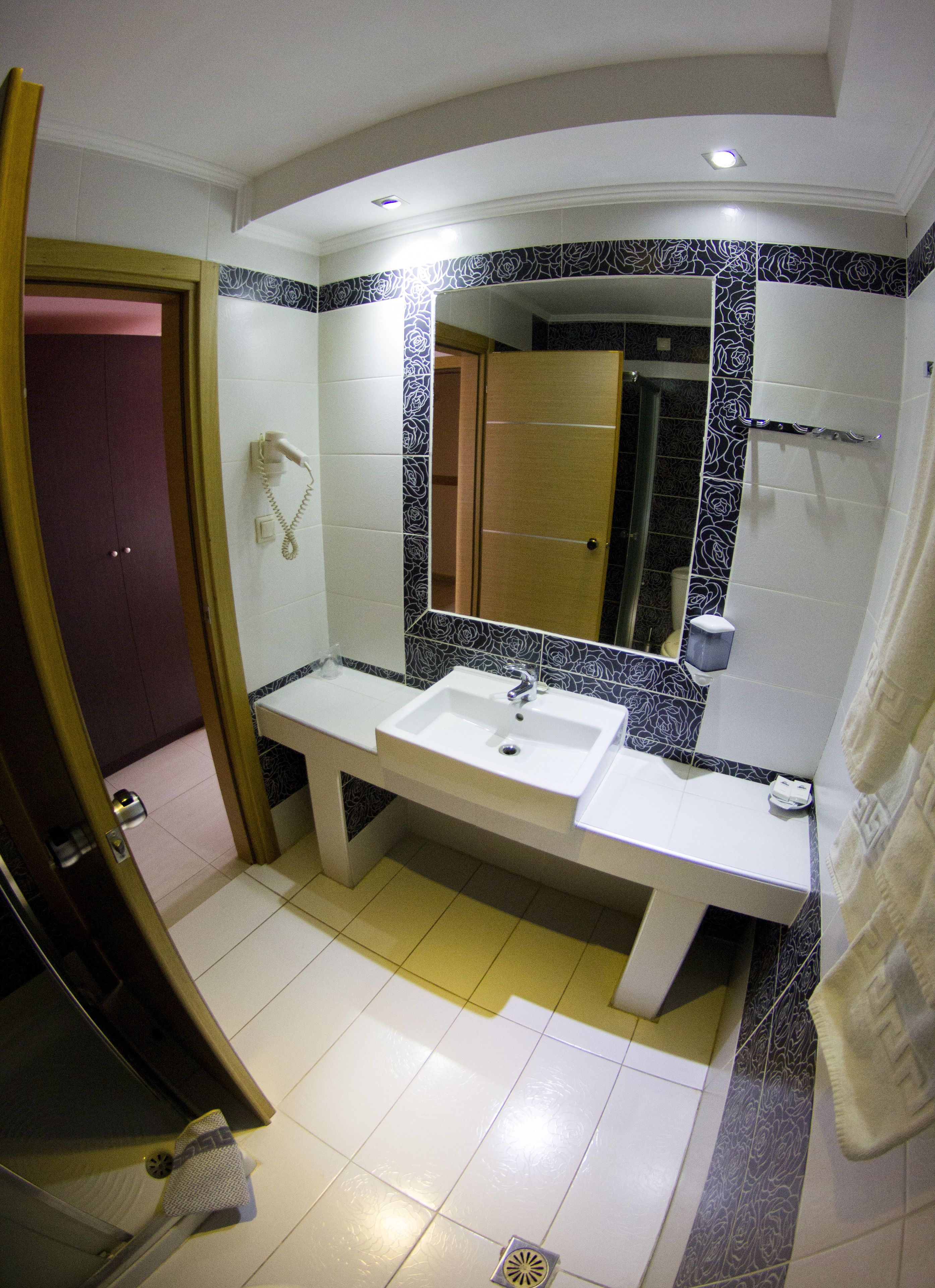 Un baño con lavamanos blanco, un espejo y zona de ducha.
