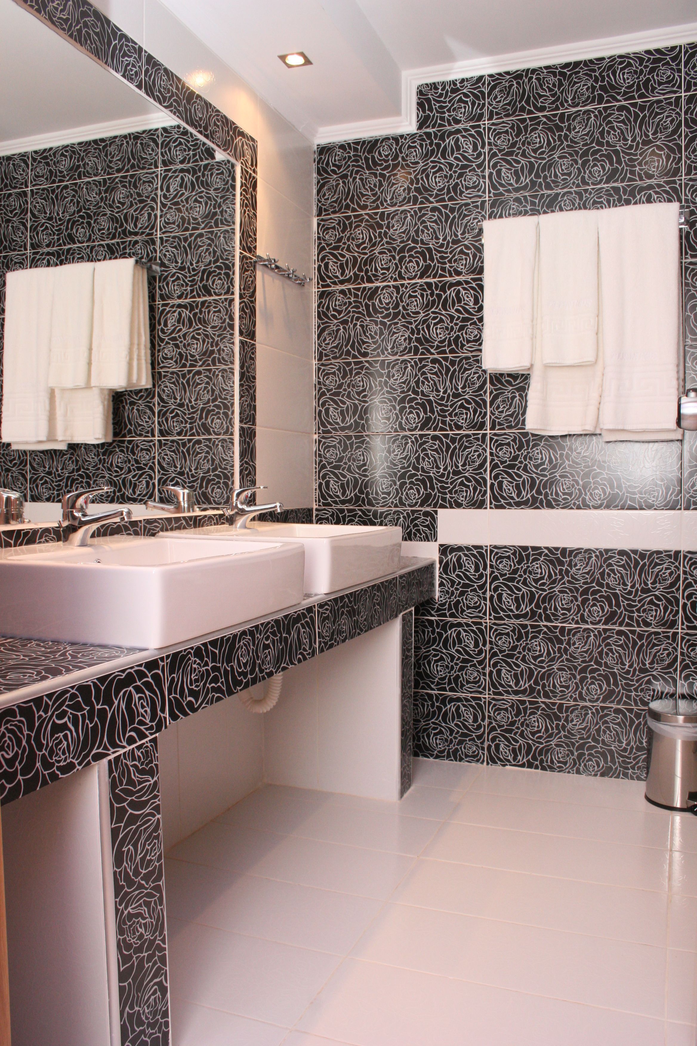 A bathroom with two sinks, a mirror, and rose-patterned tiles.