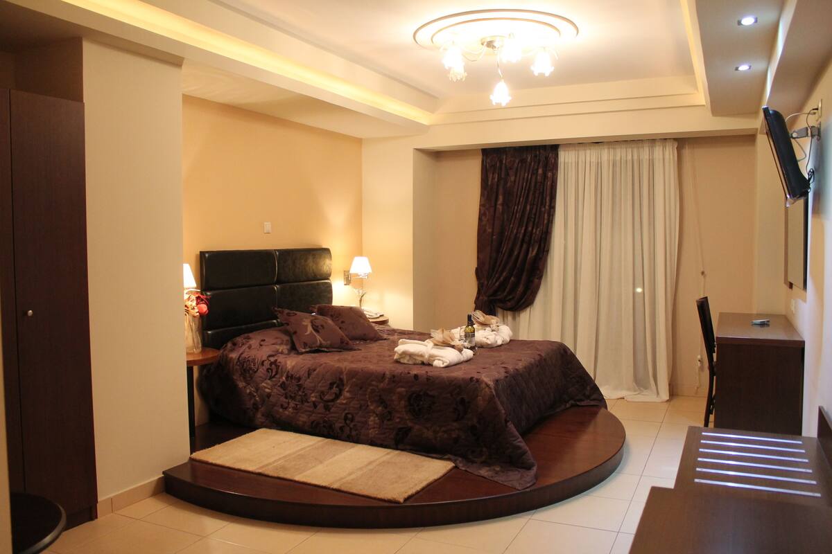 A modern bedroom with a round bed, a desk, and a television.