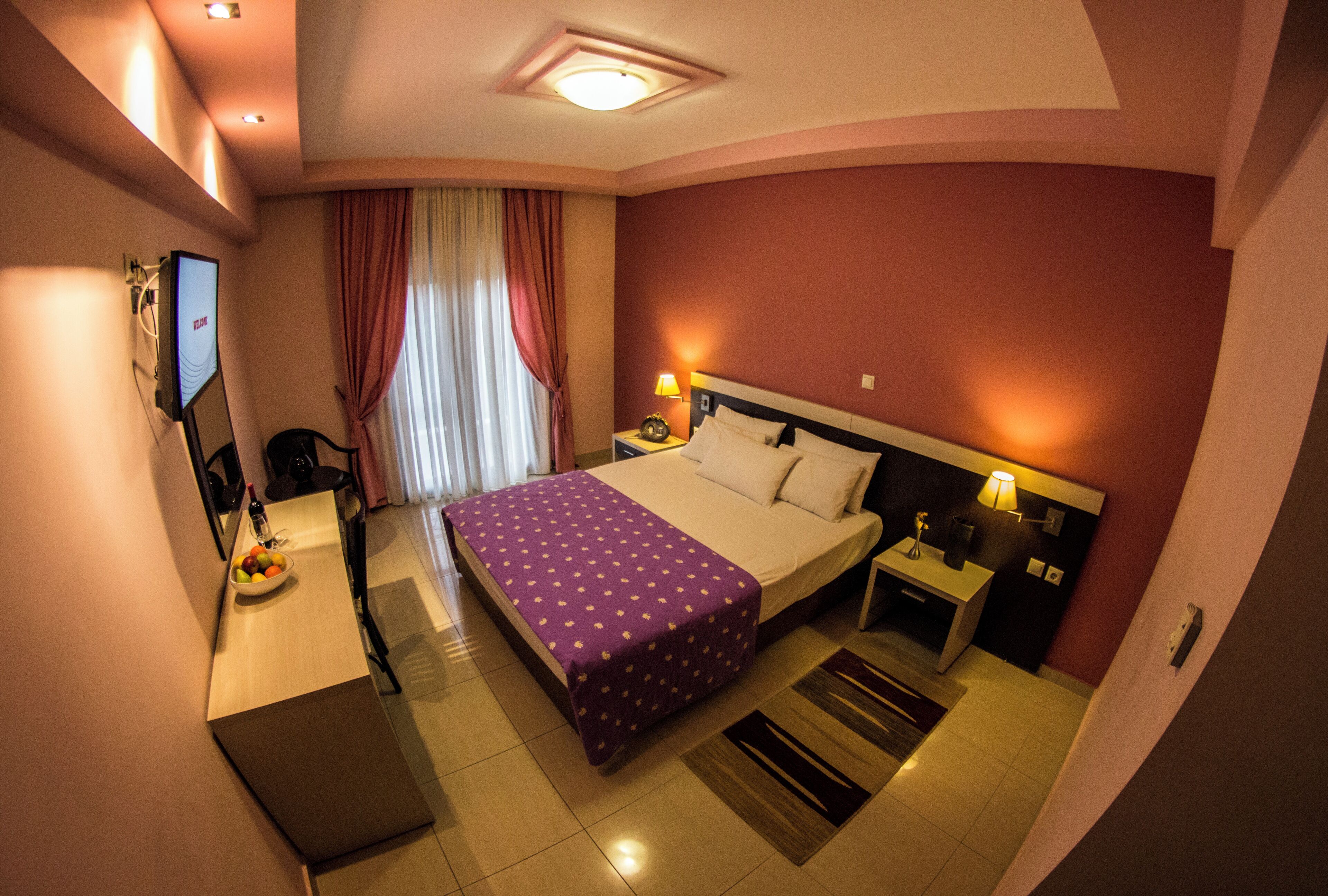 Camera d'albergo con un letto, comodini, televisione, una scrivania con sedia e un tavolo da pranzo con sedie.