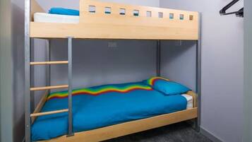 Una cama litera con un edredón estampado con motivos de arcoíris y una parte superior de madera.