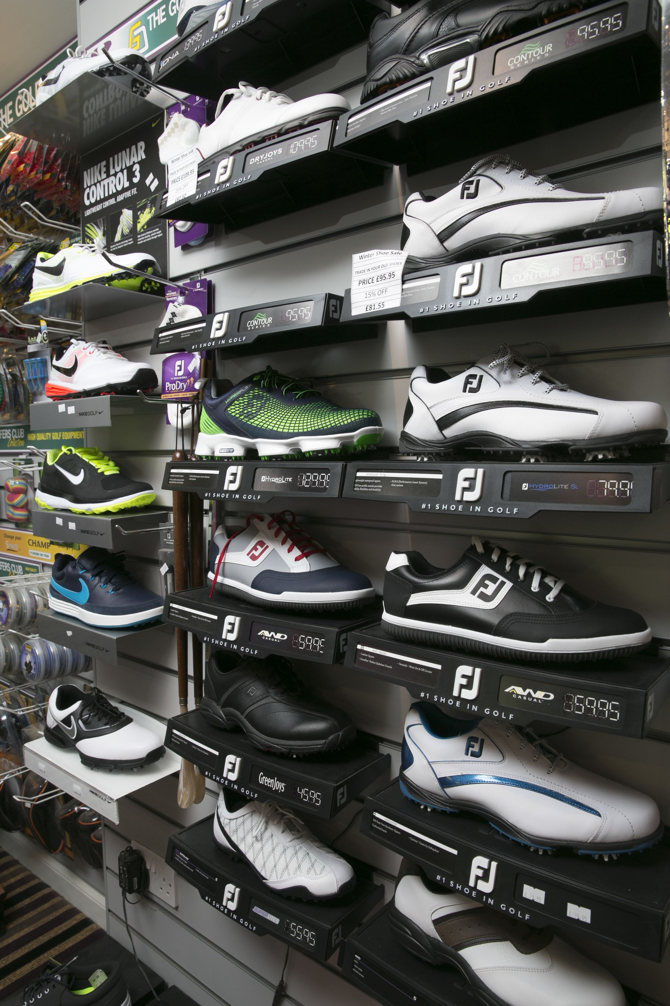 A display of golf shoes on shelves with price tags.
