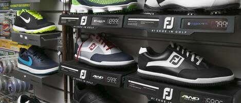 Exhibición de zapatos de golf en estantes con precios.