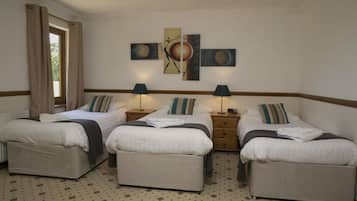 Ein Hotelzimmer mit drei Einzelbetten, einem großen Wandbild und einem Fenster mit Vorhängen.