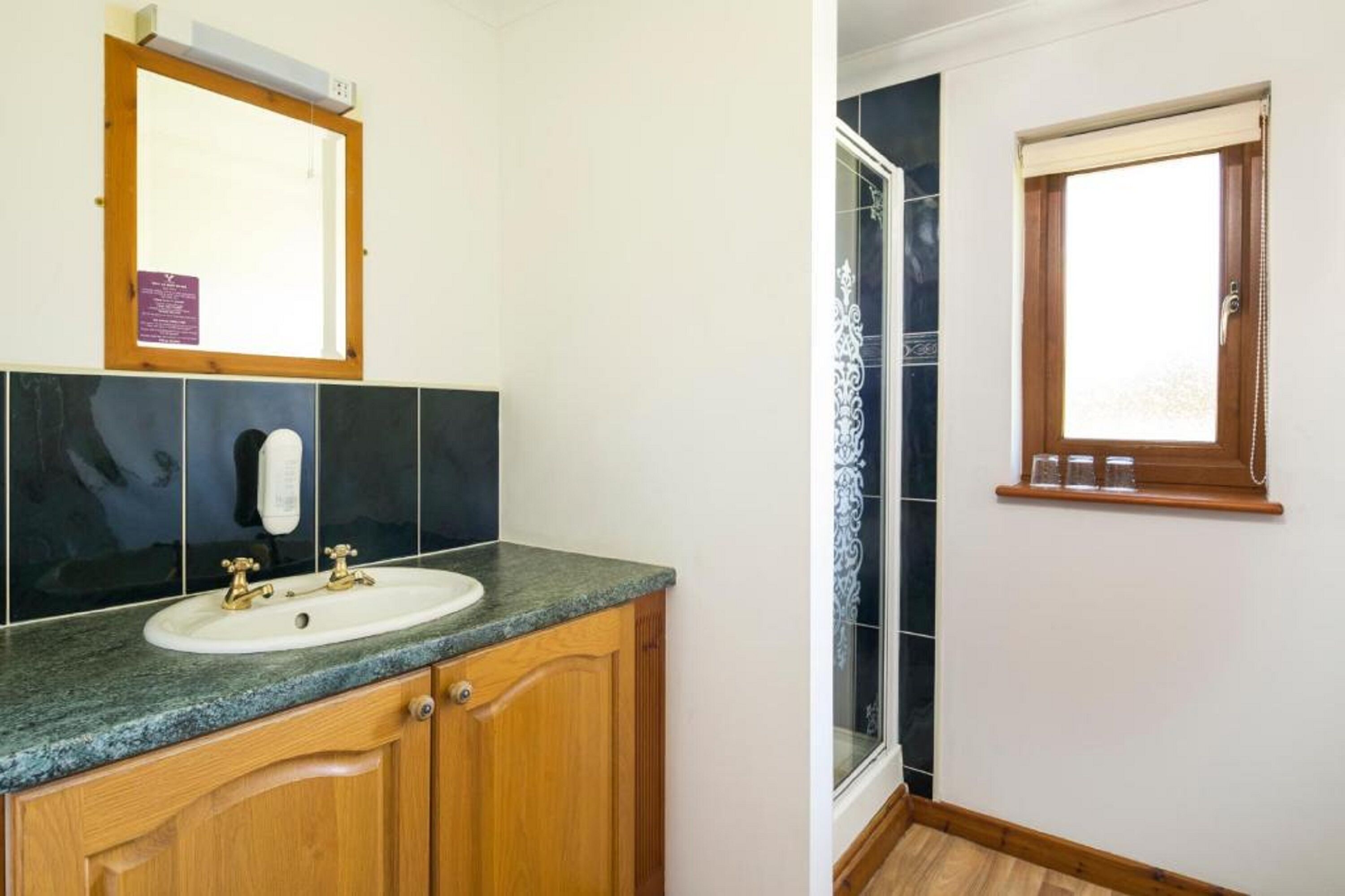 A bathroom with a wooden vanity, a white sink, and a mirror.