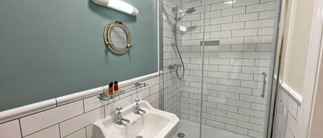 A bathroom with a sink, mirror, and glass-enclosed shower.