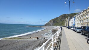 A coastal promenade with a stone sea wall, a row of parked cars, and buildings with bay windows. - The Glengower (Aberystwyth)