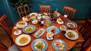 A round wooden table with various dishes and drinks, surrounded by wooden chairs. - The Glengower (Aberystwyth)